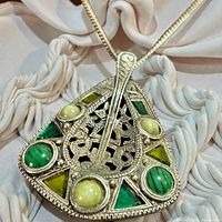 Front view of triangular Celtic pendant with green and yellow cabochons