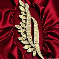 Front view of Trifari rhinestone leaf brooch on red fabric