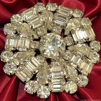 front view of circular rhinestone brooch on red fabric