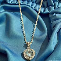 Close-up of heart pendant showing blue topaz and halo