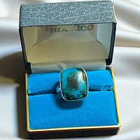 Ring in display box, showing turquoise cabochon and silver band