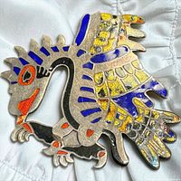 Front view showing stylized bird design and enamel colours