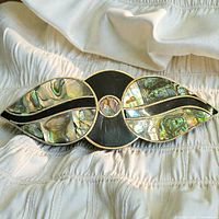 Front view of goldtone barrette with abalone shell and black inlay