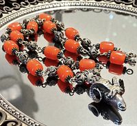 Necklace coiled on mirrored tray showing beads, spacers and pendant