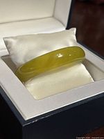 bangle resting on pillow in open box, showing top surface and color