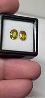 Two oval yellow-green sphenes in display box