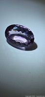 Oval faceted purple-pink amethyst lying on side