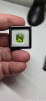 Square-cut apple-green peridot in display box, top view