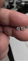 Close-up of both moissanite studs between fingers