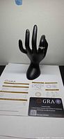 Ring on black display hand with GRA certificate card and report sheet
