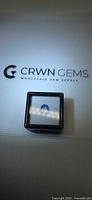 Square display box holding oval tanzanite placed on CRWN GEMS branded background