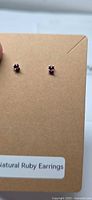 Full view of both ruby stud earrings on display card