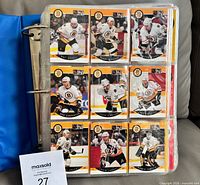 Binder open showing nine 1990-91 Pro Set Boston Bruins cards in 9-pocket page