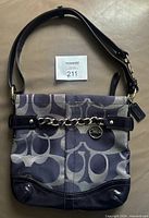 Front view of Coach shoulder bag showing signature fabric, chain accent, adjustable strap