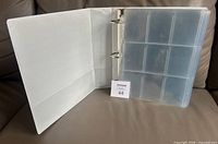 Binder open showing stack of clear nine-pocket pages inside rings