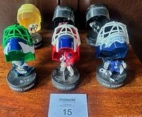 Six replica helmets with player figures displayed on wood surface
