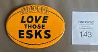 Front of yellow oval Edmonton Eskimos pinback button displaying text and football graphic
