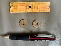Front view of two attached Expo 67 tickets, two NYC tokens, size reference pen