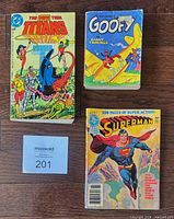 Front covers of Superman digest, Teen Titans paperback, and Goofy Big Little Book