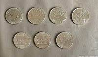 Reverse sides of seven Canadian one-dollar coins with visible dates 1975, 1977, 1982 (two), 1983, 1984, 1985