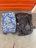 Blue floral suitcase and black rolling duffle side by side