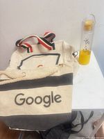 Canvas Google totes and branded water bottle arranged on table