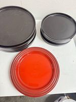 Stack of 4 black dinner plates, 4 black salad plates, and 1 red salad plate on white surface