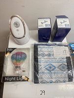 Group shot showing humidifier, two toilet paper holder boxes, packaged night light, packaged tote