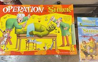 Operation Shrek Edition game box and partial view of Shrek DVDs