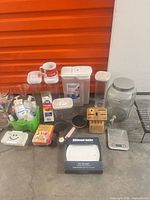 all items arranged on floor including sanitizer crate, containers, pans, scale, plates box