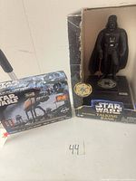 Darth Vader talking bank in open box next to sealed model kit