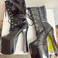Full view of both boots showing patent leather finish, laces, side zipper, platform and heel.