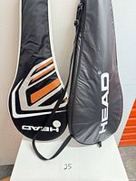 Two Head racket covers leaning against wall