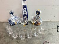 All items arranged: 8 whiskey glasses semicircle, 3 martini glasses center, 3 decorative tequila bottles back