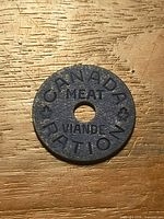 Front view of blue Canadian meat ration token showing full text and center hole