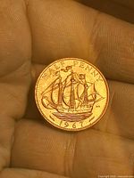 Coin on fingertip showing ship design and year 1967