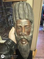 Front view of carved wood head sculpture held in hand