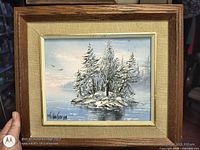 Front view of framed oil painting showing winter island scene and signature