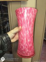 Front view of pink and white mottled glass vase held in hand