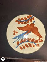 Front view of round clay pot rest showing bird and foliage design