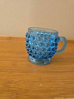 Front view of blue Dew Drop pattern glass mug with applied handle