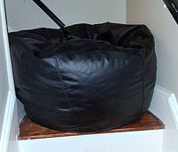 Front view of large black beanbag chair on stair landing