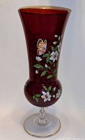 Side view showing red vase with floral and butterfly decoration, clear foot