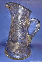 Full side view of crystal pitcher showing floral cuts and handle