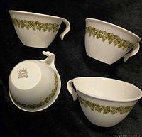 Four Corelle Spring Blossom Green teacups, three upright, one inverted to show pattern and handle style
