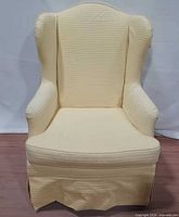 Front view of yellow wingback chair showing upholstery and shape