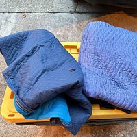 Two folded navy blue quilted cotton tarps on storage bin lid