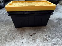 Front view of one black storage tote with yellow lid