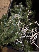 Tree branches, lights and garland inside plastic bin