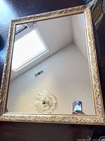 Front view of rectangular gold framed mirror on flat surface